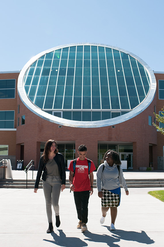 Three students walking in front of the library 17