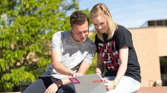 Students looking at a laptop outdoors